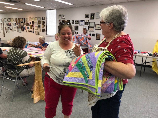 Tina Withers receives a quilt from Susan Stallings of Community Quilts.